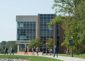 A modern building sits along a sidewalk with students walking