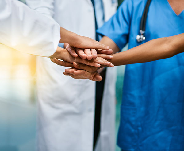 Medical personelle with hands stacked in agreement