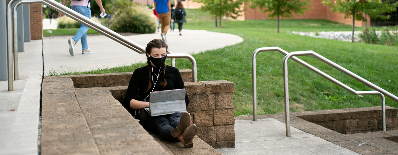 Student working on computer on steps in front of BTS
