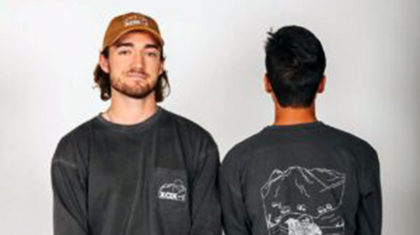 Two Pursuit business members wearing their company's shirts and ball cap