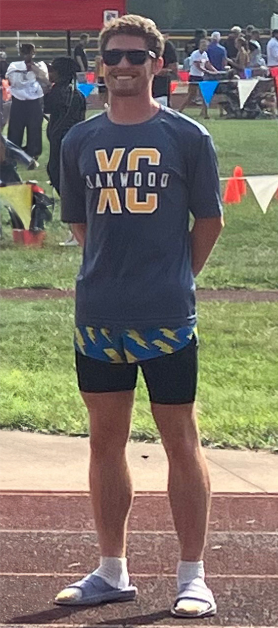 Coach Ramen Felumlee smiling standing on outdoor track.