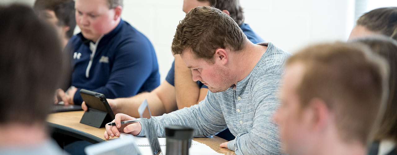 Male student takes notes in class