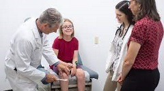 PA professor examines a girl while students look on.