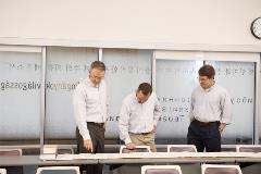 3professorslookatunrolledscrollontable