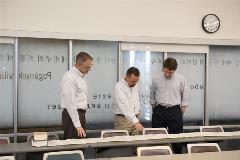 3professorslookatunrolledscrollontable