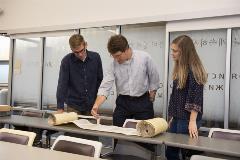 2studentswithDrShepherdlookatpartiallyopenTorahscroll