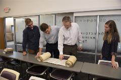 2studentswithDrShepherdandDrMcKinionlookatpartiallyopenTorahscroll
