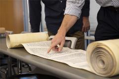 TorahScrollrolledoutontablewithpeoplepointingandanalyzingit