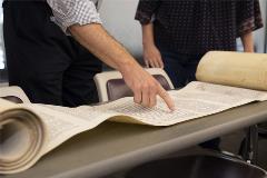 TorahScrollrolledoutontablewithpeoplepointingandanalyzingit